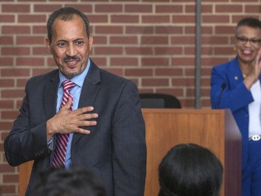 Man giving a speech at a professional event, engaging with the audience, with a smiling woman in the.