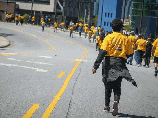 Protesters in yellow shirts walking on city street during demonstration, advocating for social chang.