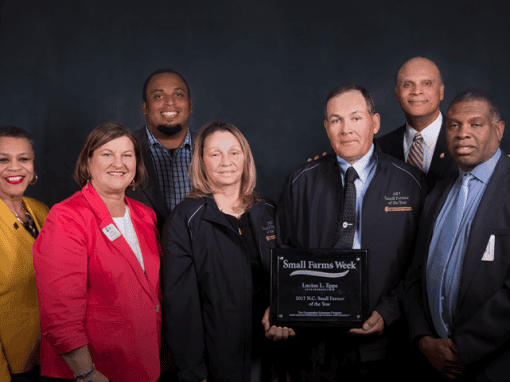 Group of CAES leaders and farmers celebrating Small Farms Week, holding an award plaque.