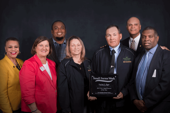 Group of CAES leaders and farmers celebrating Small Farms Week, holding an award plaque.