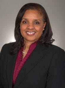 A professional woman in business attire smiling, representing leadership and success in the news ind.