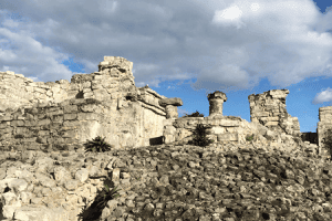 Ancient Mayan ruins with stone structures and lush surroundings in Mexico.
