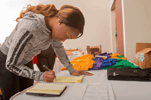 Woman organizing colorful T-shirts and supplies for event at CAES News.