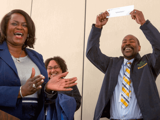 Group of professionals celebrating success at CAES News event, smiling and clapping.