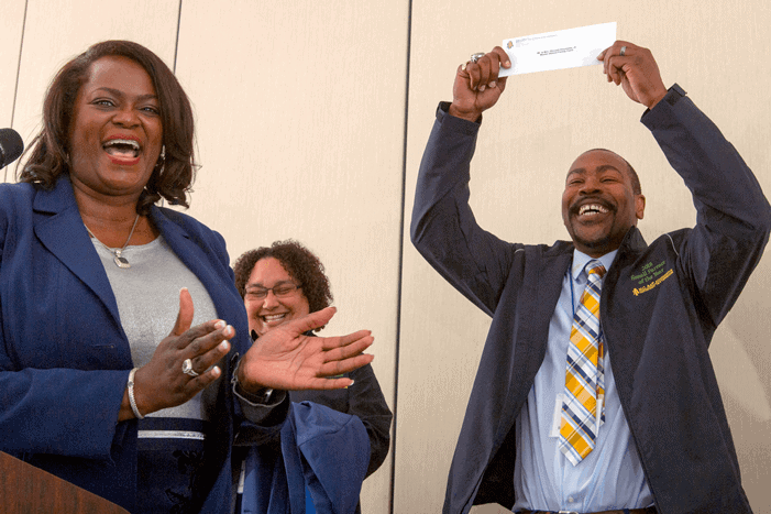 Group of professionals celebrating success at CAES News event, smiling and clapping.