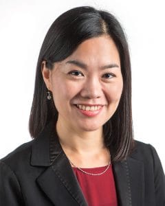 Woman in business suit smiling, representing leadership and success in news coverage.