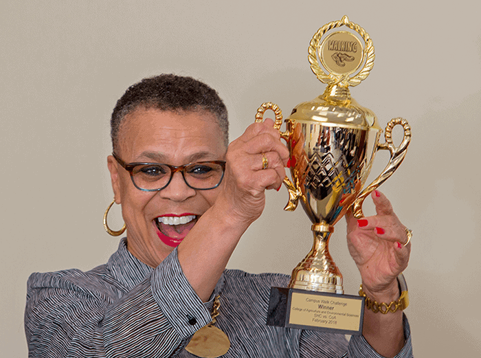 An inspiring woman holding a gold trophy, celebrating success and victory.