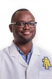 Professional medical doctor wearing white coat with CAES logo, smiling.