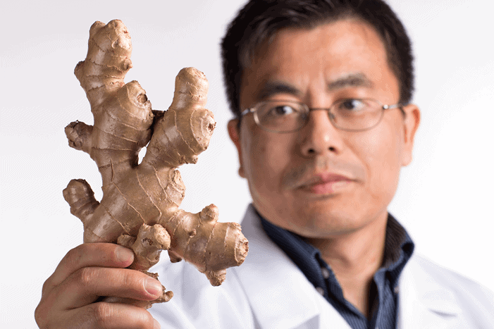Man holding fresh ginger root, promoting natural health remedies.