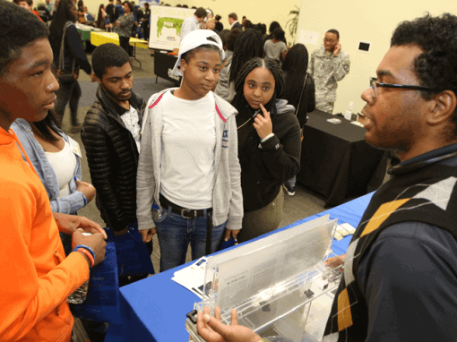 Students engaging with a STEM demonstration at a science fair.