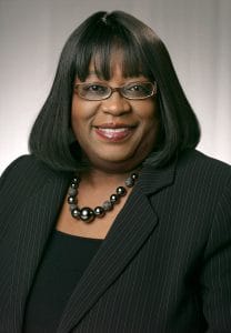 Professional woman in business attire with glasses, smiling for CAES News.