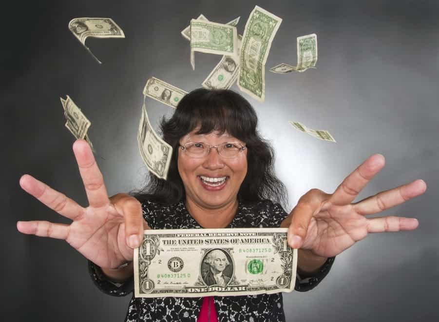 Money raining over happy woman with dollar bills flying around.