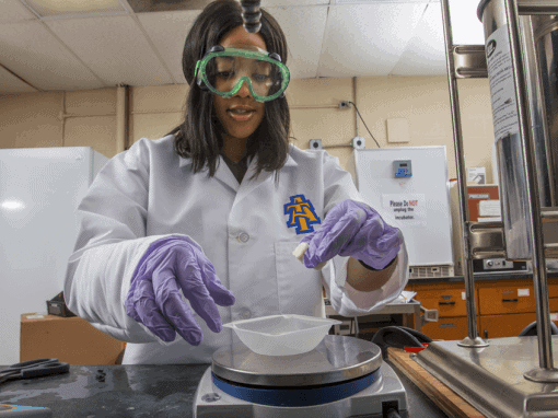 Scientist in laboratory wearing safety goggles and gloves, working with scientific equipment.