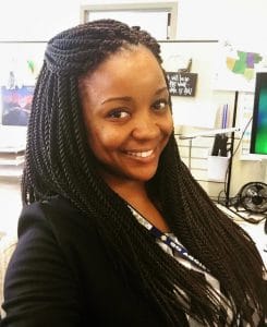 A woman with braided hair smiling in an office environment.