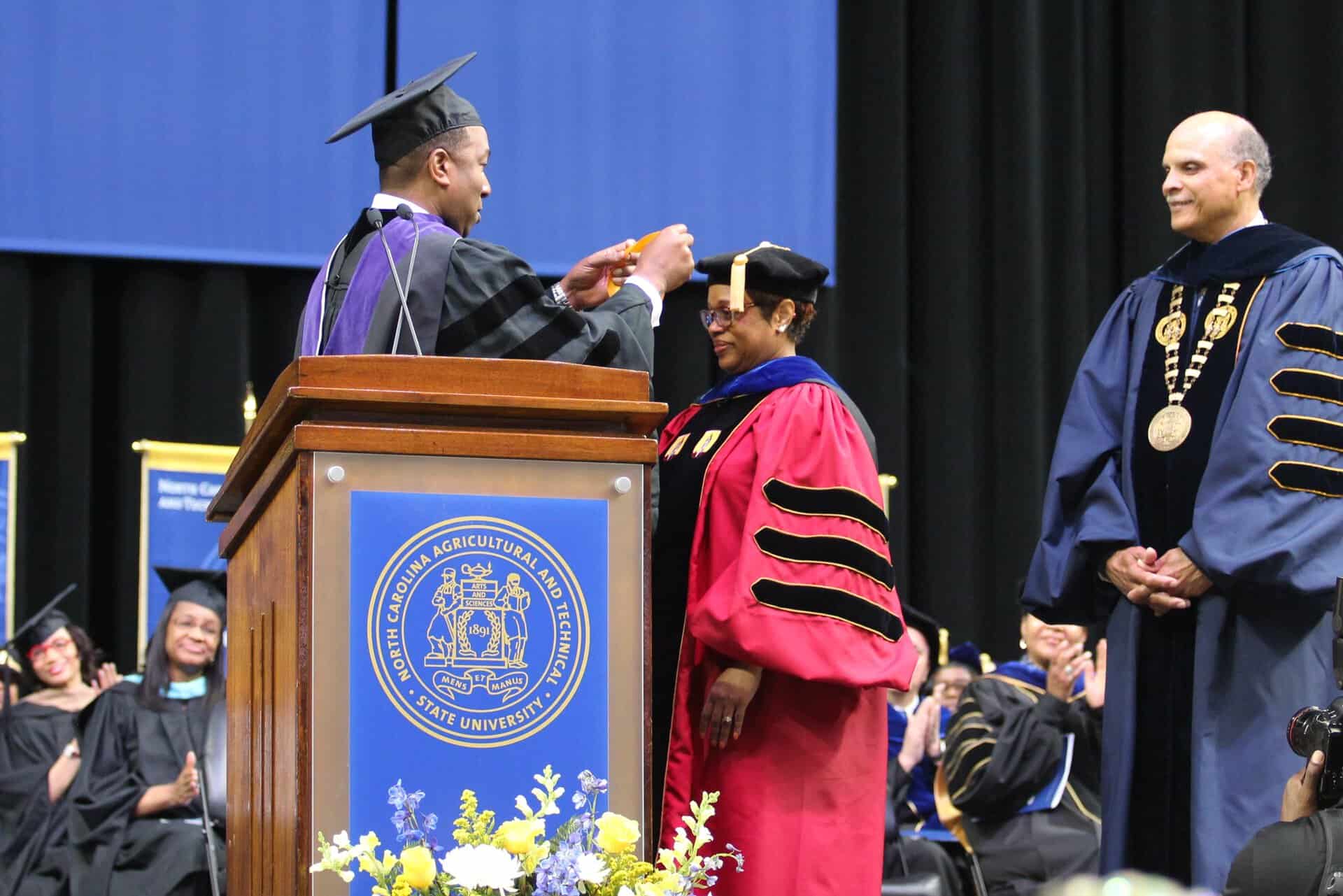 University graduation ceremony with graduates in caps and gowns on stage.