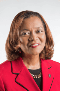 Empowered woman in red blazer speaking at a conference for leadership and diversity.