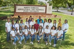 A woman and students standing in front of North Carolina A&T State University sign.