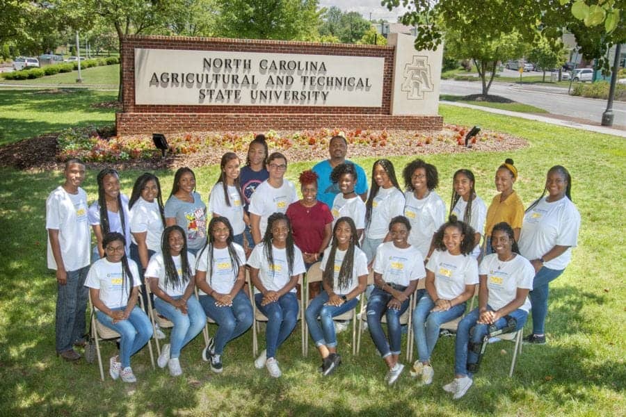 A woman and students standing in front of North Carolina A&T State University sign.