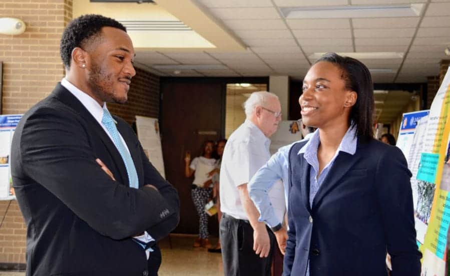 A woman and a man engaging in conversation at a professional event or conference.