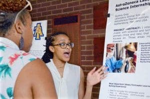 A woman presenting scientific research at a poster session during a conference.