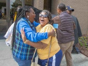 Celebrating community and friendship with joyful smiles and warm embraces outside a building.
