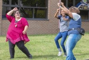 Enjoying outdoor dance and celebration with friends on a sunny day.