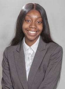 A woman in a gray business suit smiling at the camera.