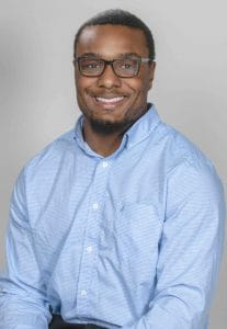 Professional smiling man in glasses wearing a blue shirt for CAES News.