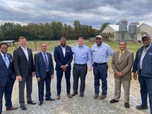 Group of diverse professionals standing outdoors at a farm or industrial site.