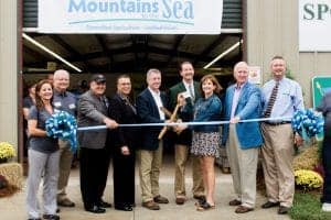 New agricultural facility opening ribbon-cutting ceremony with diverse group of professionals.