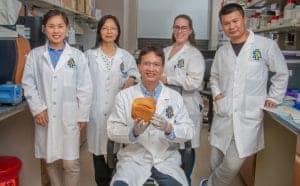 A scientist holding a bread sample in a laboratory setting with diverse team members.