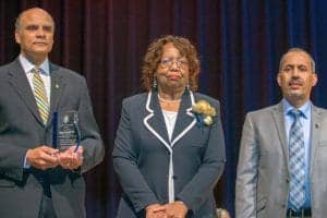 Award ceremony with three distinguished individuals on stage, celebrating achievements at CAES News.