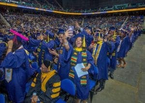 Graduates celebrating at a commencement ceremony in a large stadium.