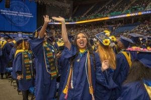 Graduates celebrating at a university graduation ceremony in caps and gowns.