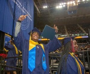 Graduation ceremony at a university with students in caps and gowns celebrating achievement.