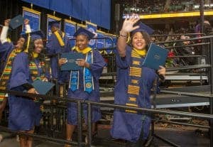 Graduates celebrating at a graduation ceremony in caps and gowns.