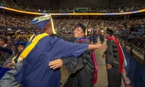 Graduation ceremony with graduates in caps and gowns celebrating success at a large indoor venue.
