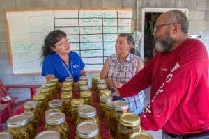 Canned food jars displayed at CAES News event with two women and a man discussing.