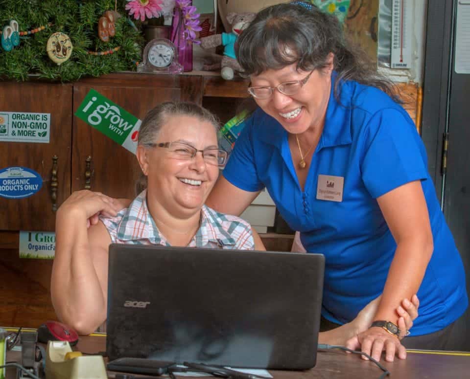 Happy customer and staff member using a laptop at a store counter.