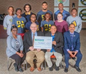 Group of diverse students and professionals celebrating donation at CAES News event.