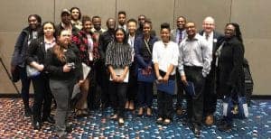 Diverse group of professionals at a conference, smiling and posing for a photo indoors.