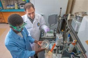 A scientist and a student working together in a laboratory setting, conducting an experiment with sc.