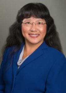 A woman in a blue blazer smiling, professional portrait for CAES News.