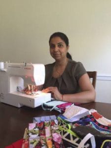 Sewing woman working with fabric and sewing machine at home.