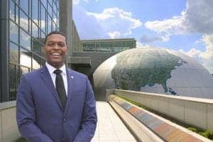 Business professional smiling outside modern building with globe sculpture in background.