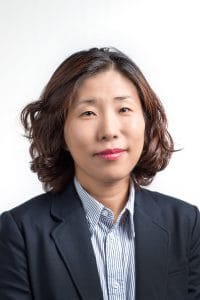 Professional Asian woman in business attire, smiling confidently for corporate headshot.