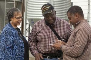 Veteran and two men discussing outdoors at a community event, smiling and engaging in conversation.