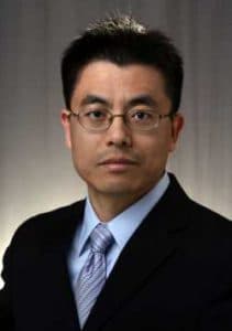 A man in a suit and glasses looking serious, professional portrait.
