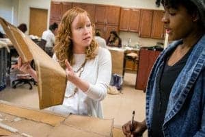 Constructive discussion between two women working on a project in a classroom or workshop setting.