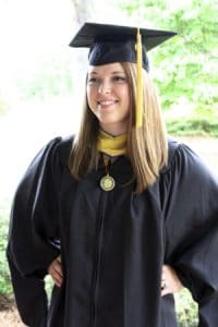 Graduation woman in cap and gown smiling outdoors at CAES News.